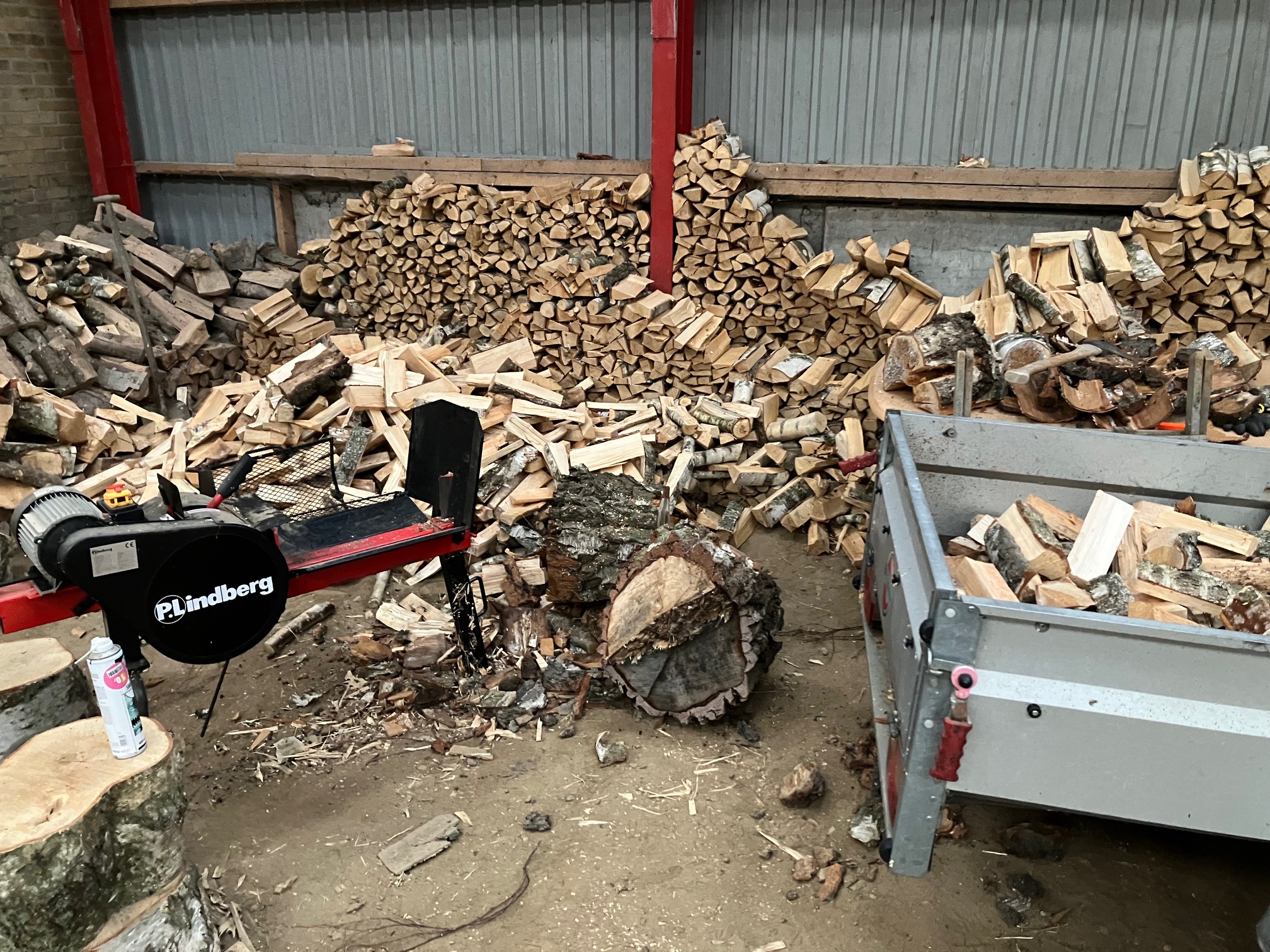 Birkebrænde bliver kløvet og stablet i stålladen på ejendommen.